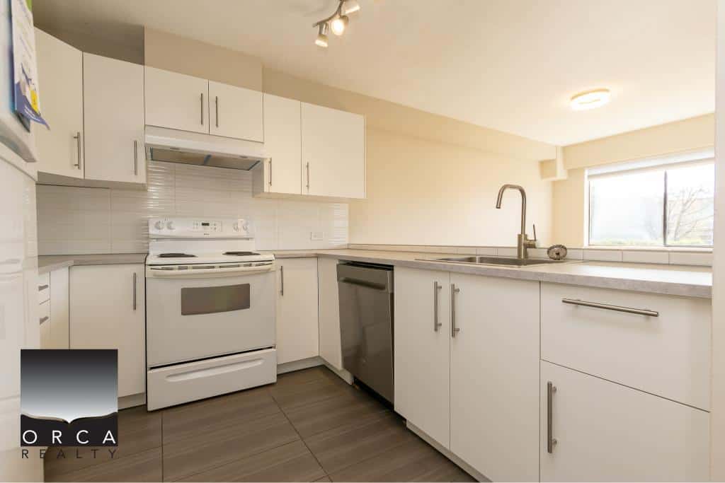 Modern white kitchen with stainless steel appliances and ample cabinetry, perfect for homebuyers and real estate investors in Vancouver.