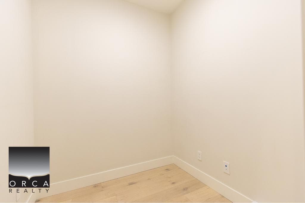 Bright empty room with white walls and hardwood flooring, ideal for use as a home office or bedroom in a Vancouver area property. Modern interior design suitable for residential real estate listings.