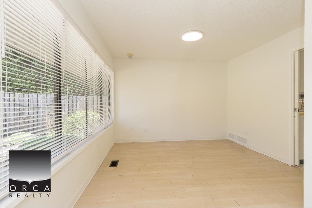 Bright empty living room with large windows, white walls, and hardwood flooring, ideal for homebuyers seeking a modern and spacious property in BC.
