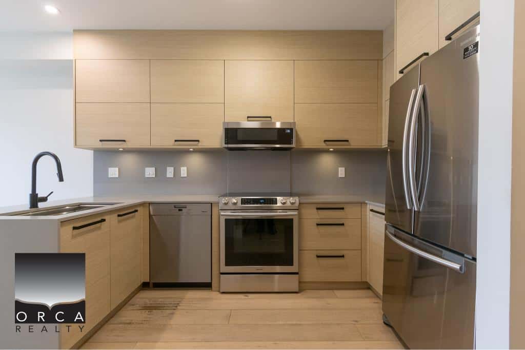 Modern kitchen with stainless steel appliances, light wood cabinets, and a sleek black faucet, perfect for contemporary home living in Ontario.