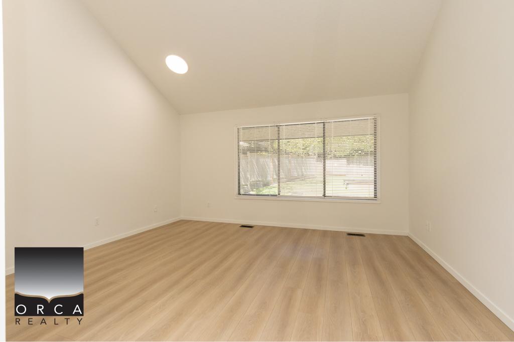 Bright vacant living room with large window and neutral decor, perfect for showcasing properties in Victoria, BC. Ideal for real estate listings by Orca Realty Inc.