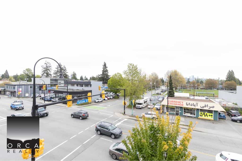 Spacious commercial street view with retail stores, currency exchange, and busy traffic, ideal for local businesses and real estate opportunities in Orca Realty Inc. service area.