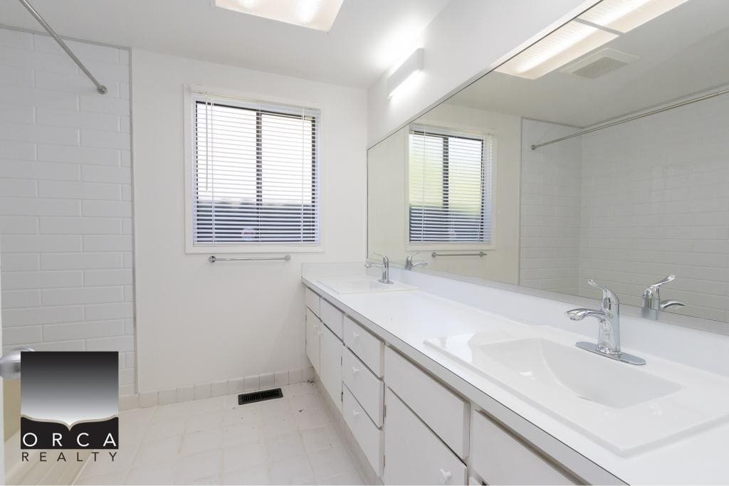 Bright modern bathroom with dual sinks, white cabinetry, and large mirror in a Vancouver Island home — perfect for relaxing and daily routines.