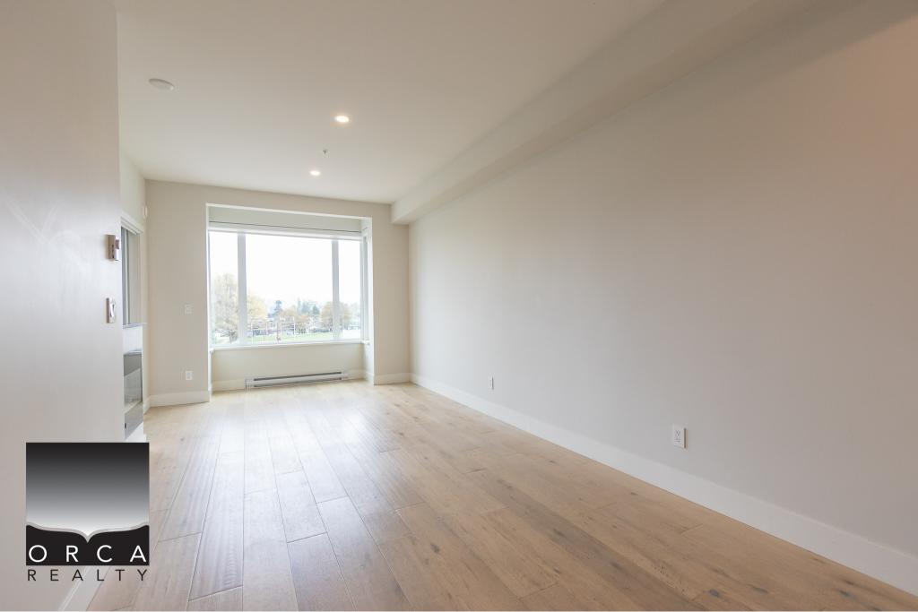 Bright minimalist living room with large window, natural light, light hardwood flooring, and white walls showcasing modern residential interiors.