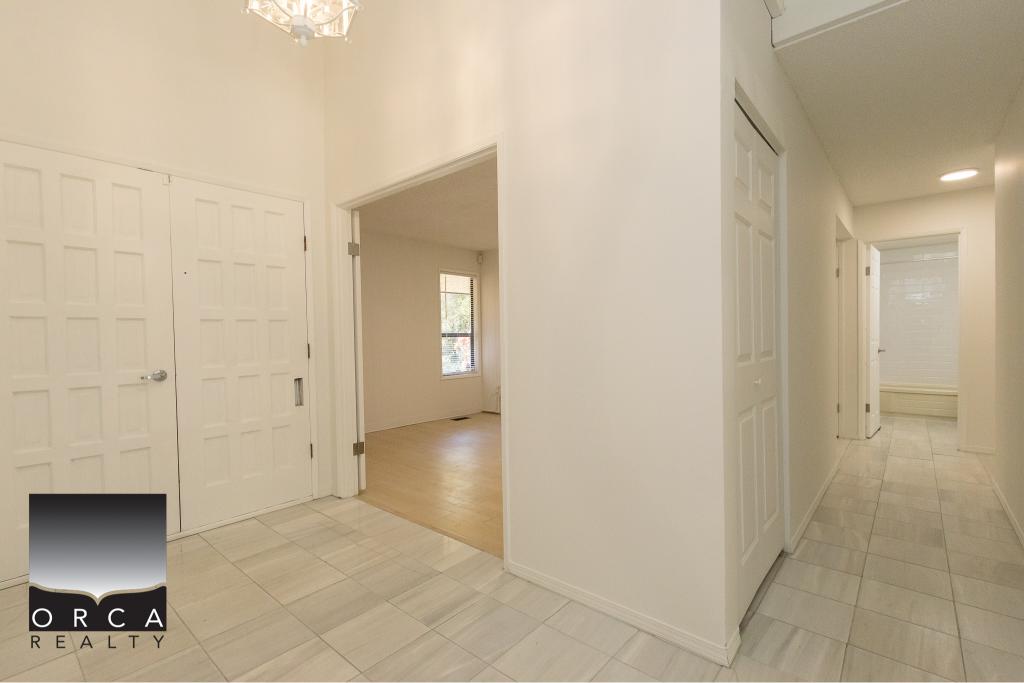 Bright white hallway in a modern Vancouver Island home, featuring closet storage, natural light, and seamless flow to living areas, perfect for family living and urban comfort.