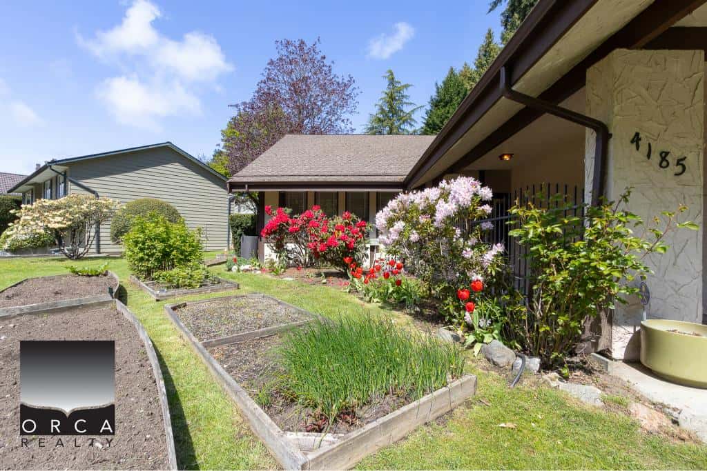 Colorful garden with blooming flowers and well-maintained landscaping outside a residential home in a neighbourhood in Vancouver, BC.