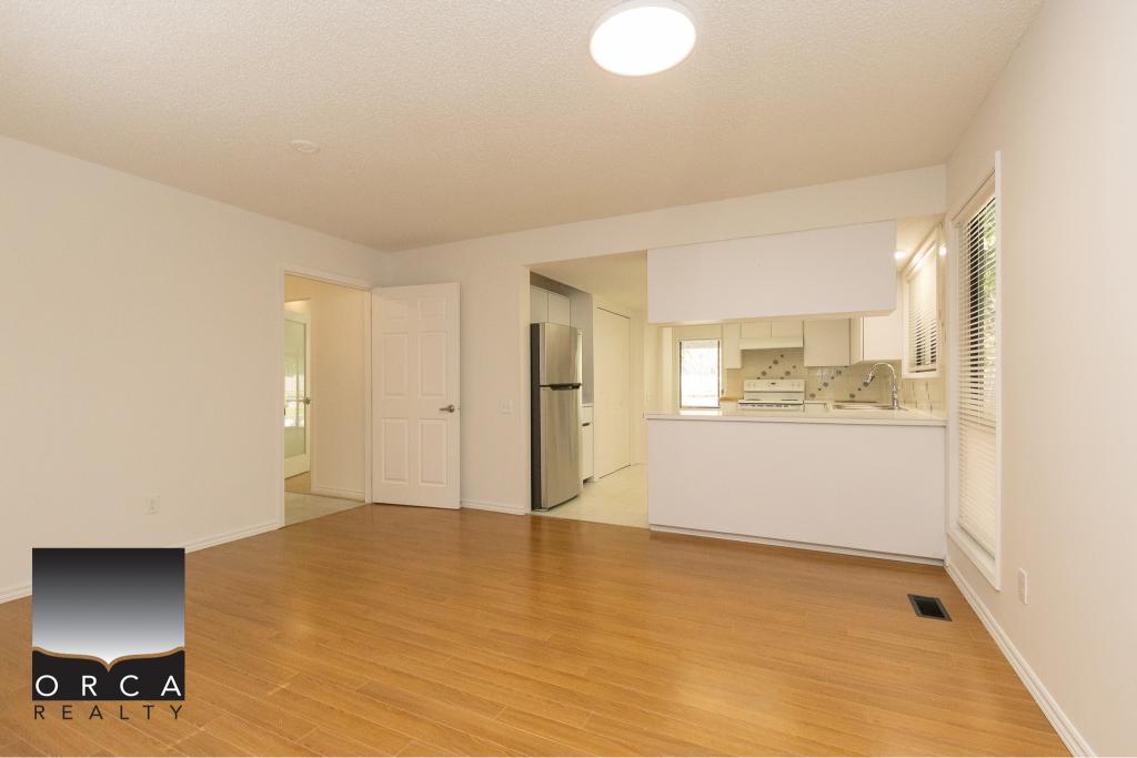 Bright, open-concept kitchen and living area in a Vancouver Island property, showcasing modern appliances and hardwood flooring, ideal for buyers seeking seaside homes.