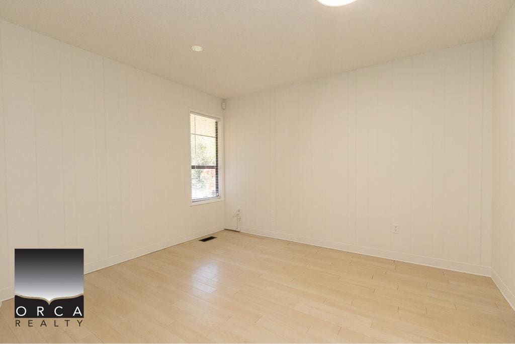 Bright empty room with white walls and light wooden flooring, showcasing a clean, modern interior perfect for new homeowners or tenants in Vancouver.