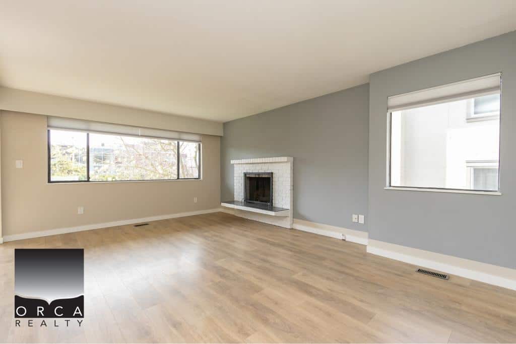 Bright spacious living room with large windows, neutral walls, and a cozy fireplace, perfect for Vancouver homebuyers seeking modern real estate options.