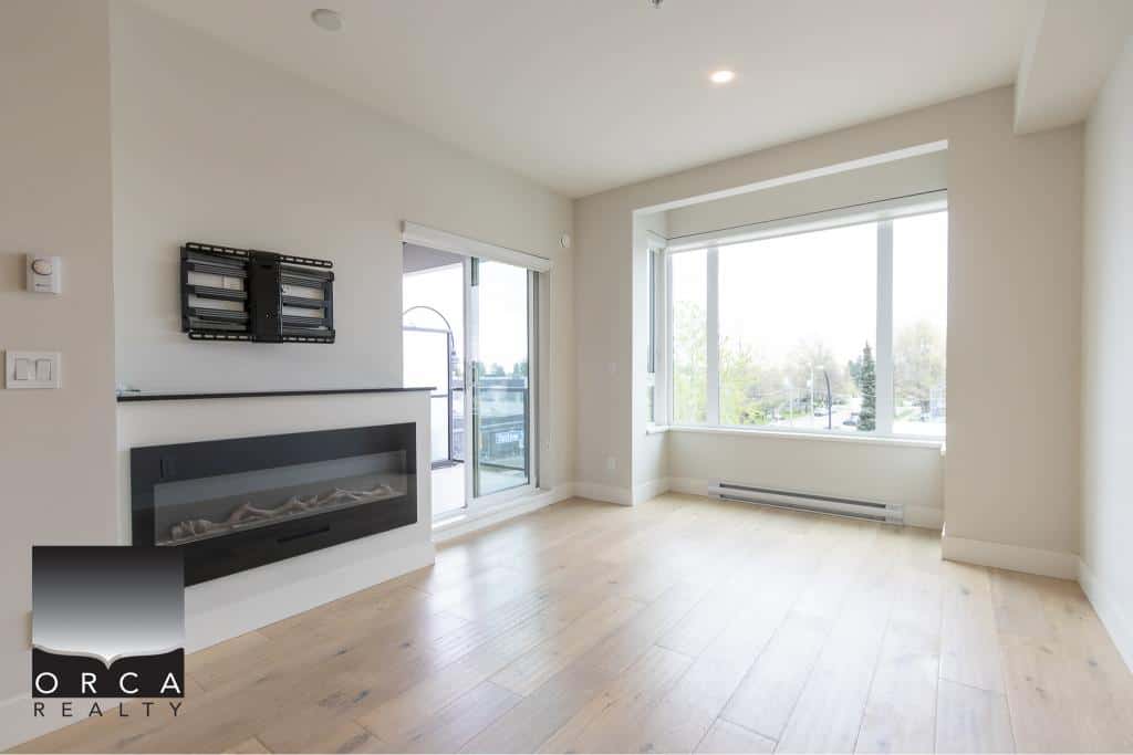 Modern bright living room with large windows, hardwood flooring, and electric fireplace, offering prime real estate opportunities in Vancouver area.