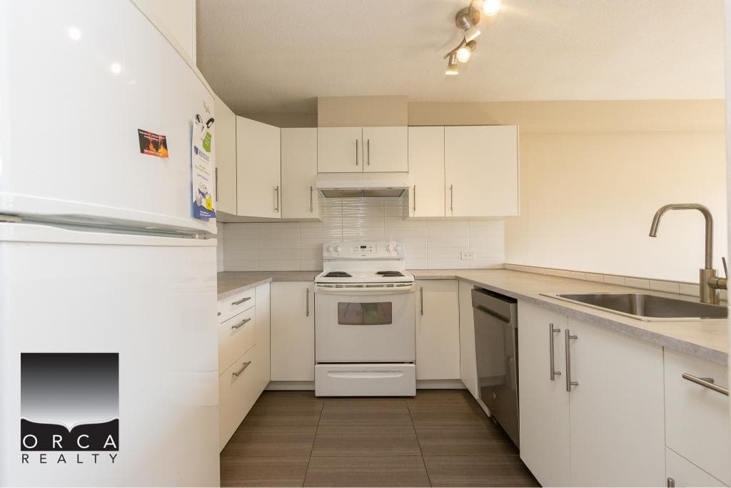 Bright modern kitchen with white cabinets, stainless steel appliances, and ample counter space, perfect for Vancouver Island real estate buyers.