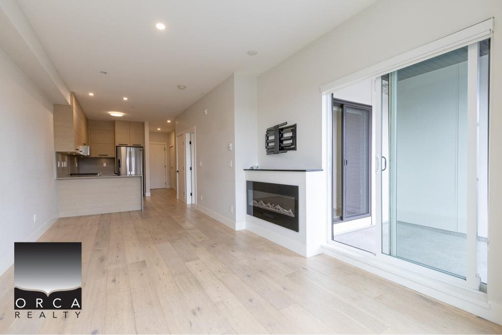 Modern open-concept living space with hardwood floors, large sliding glass doors, and a stylish electric fireplace, perfect for Vancouver real estate buyers.