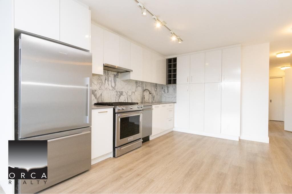Spacious Vancouver condo kitchen featuring white cabinetry, marble backsplash, and stainless steel fridge and oven, ideal for urban living at 407-231 E Pender St.