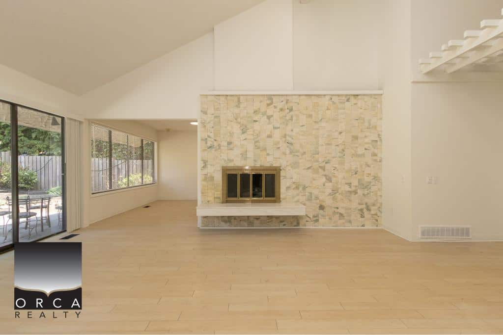 Modern living room with fireplace and large windows showcasing outdoor patio, ideal for Vancouver Island real estate buyers.