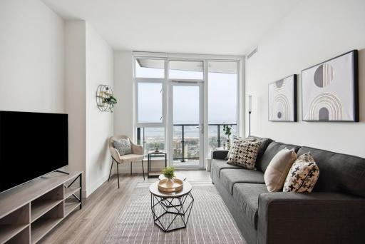 Modern living room with large floor-to-ceiling windows, stylish sofa, and contemporary decor, showcasing Vancouver condo interior for Orca Realty Inc.