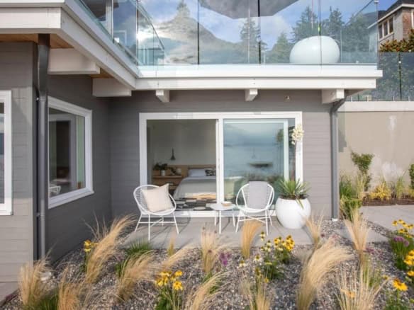 Modern waterfront home with outdoor patio, stylish furniture, and scenic mountain views in Orca Realty Inc. property listings.