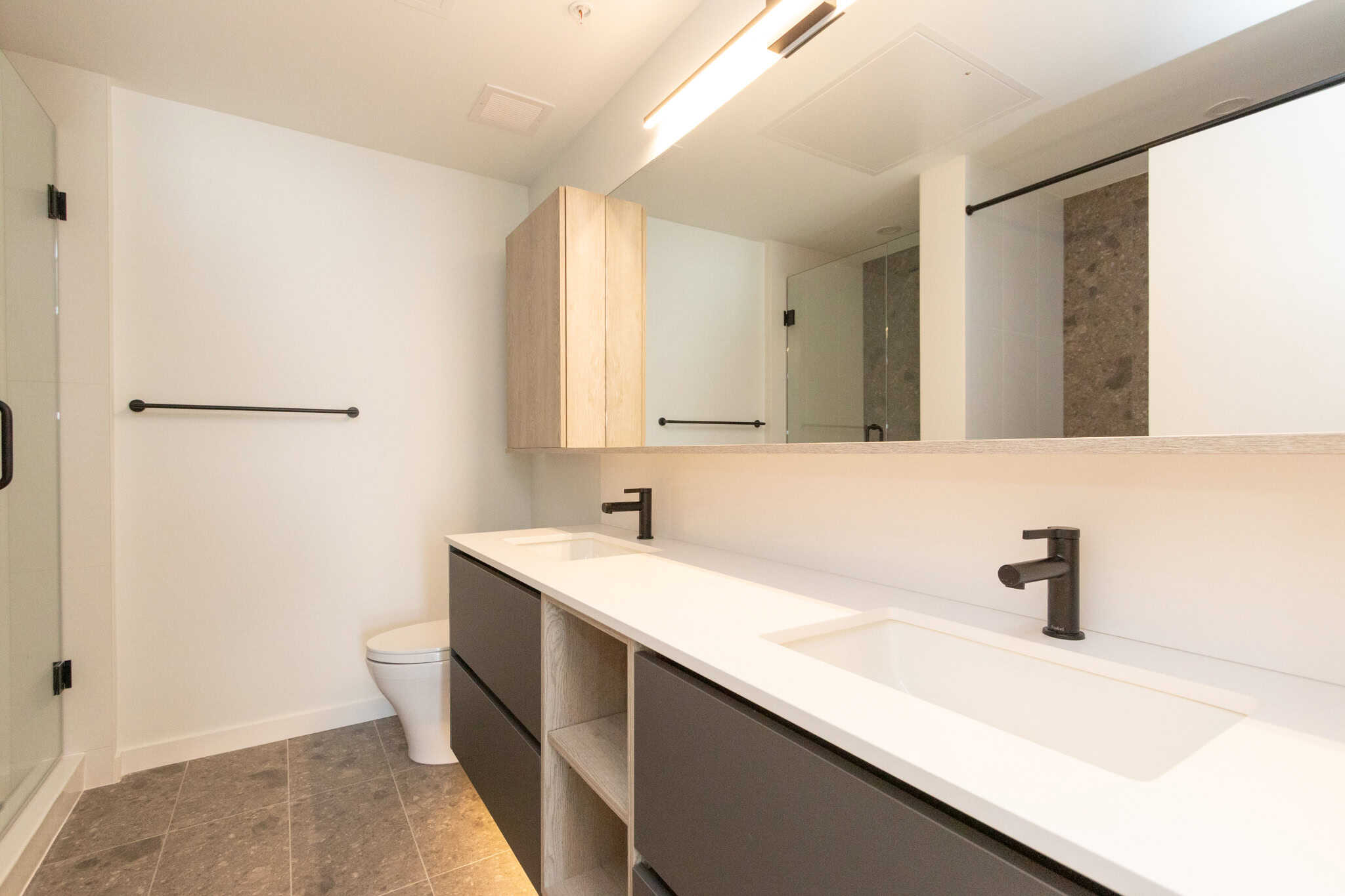 Modern bathroom with double vanity, sleek black fixtures, neutral tones, and contemporary design, perfect for Vancouver-area real estate listings.