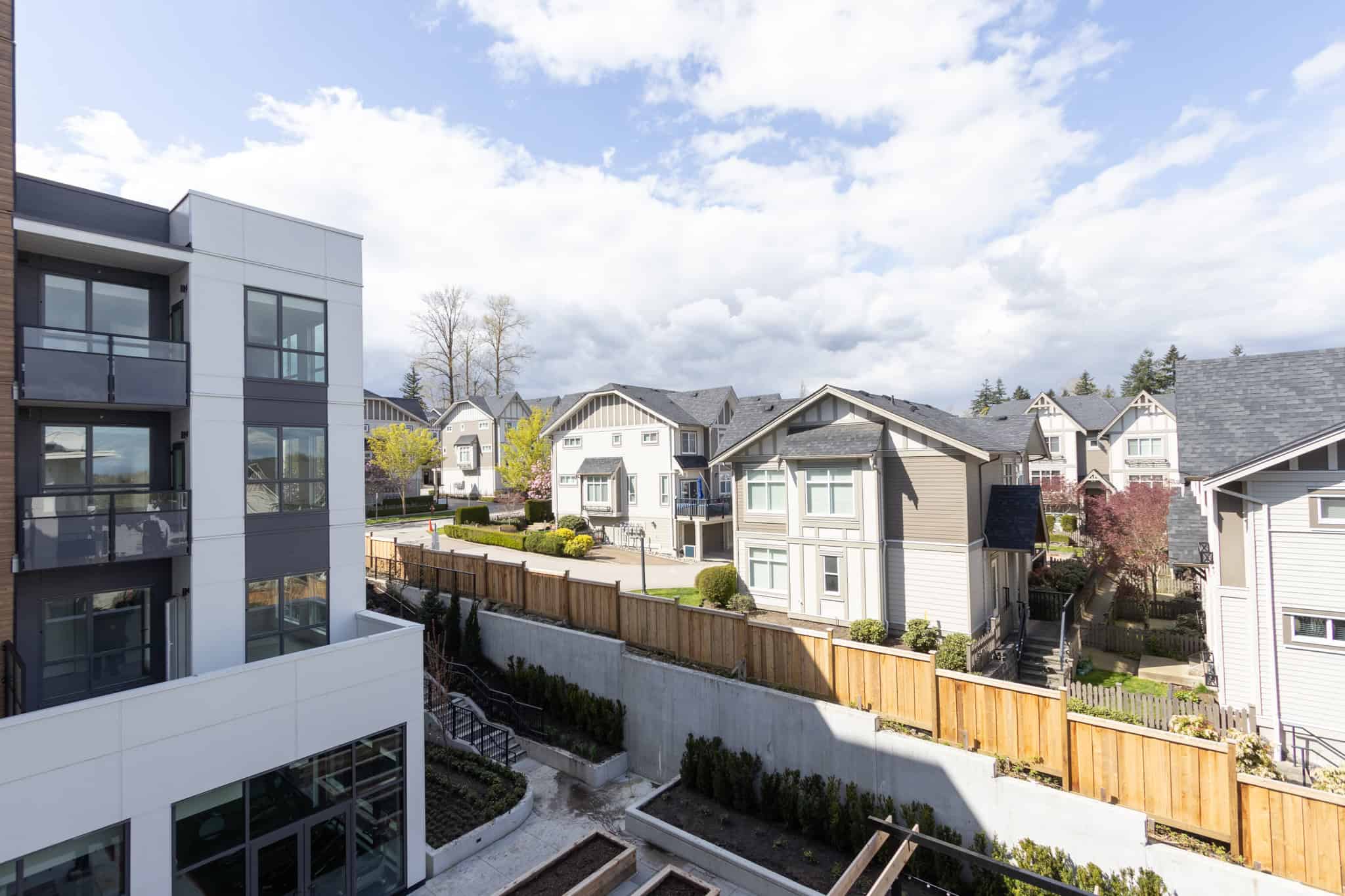 Modern residential neighborhood featuring contemporary condos and classic single-family homes in a vibrant, family-friendly community. Beautiful trees and well-maintained landscaping enhance the inviting atmosphere.