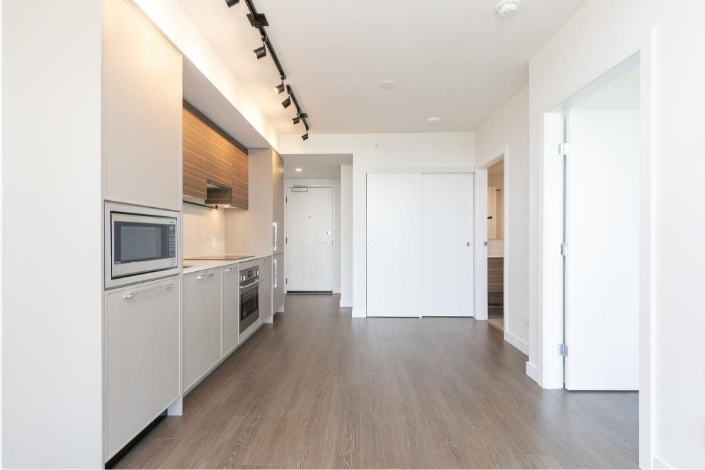Contemporary kitchen with modern appliances, sleek cabinetry, and hardwood flooring in a stylish BC apartment. Perfect for urban living and showcasing Orca Realty Inc.’s real estate expertise.