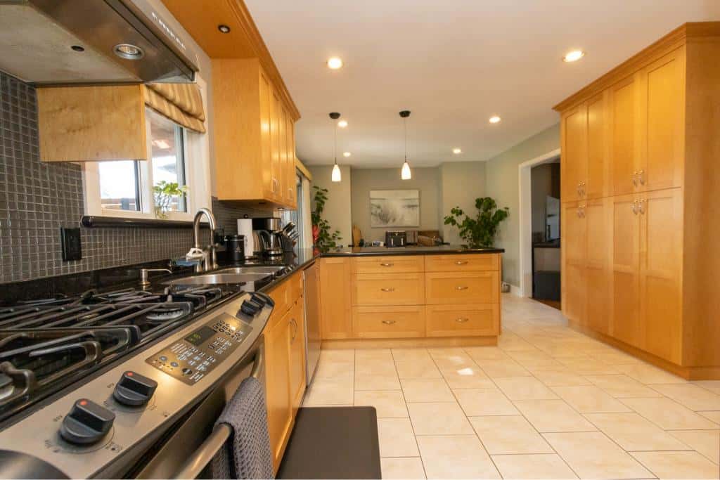 Bright, modern kitchen featuring wooden cabinetry, stainless steel appliances, and a tiled floor, perfect for family living and entertaining in Vancouver’s real estate market.