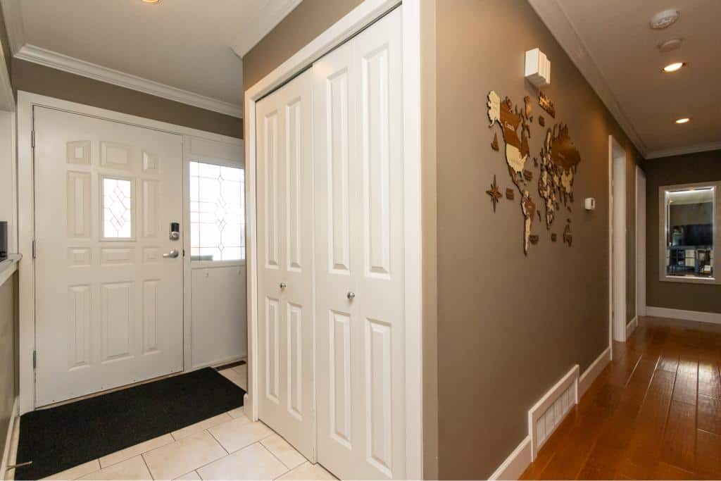 Modern home entryway with white door and decorative window, showcasing welcoming interior design and organized storage space.