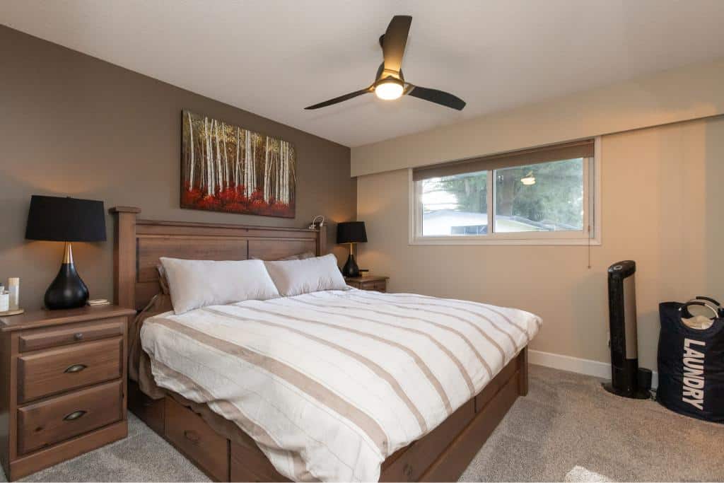 Modern bedroom with a wooden bed frame, stylish nightstands, and a large window offering natural light - perfect for Vancouver real estate.