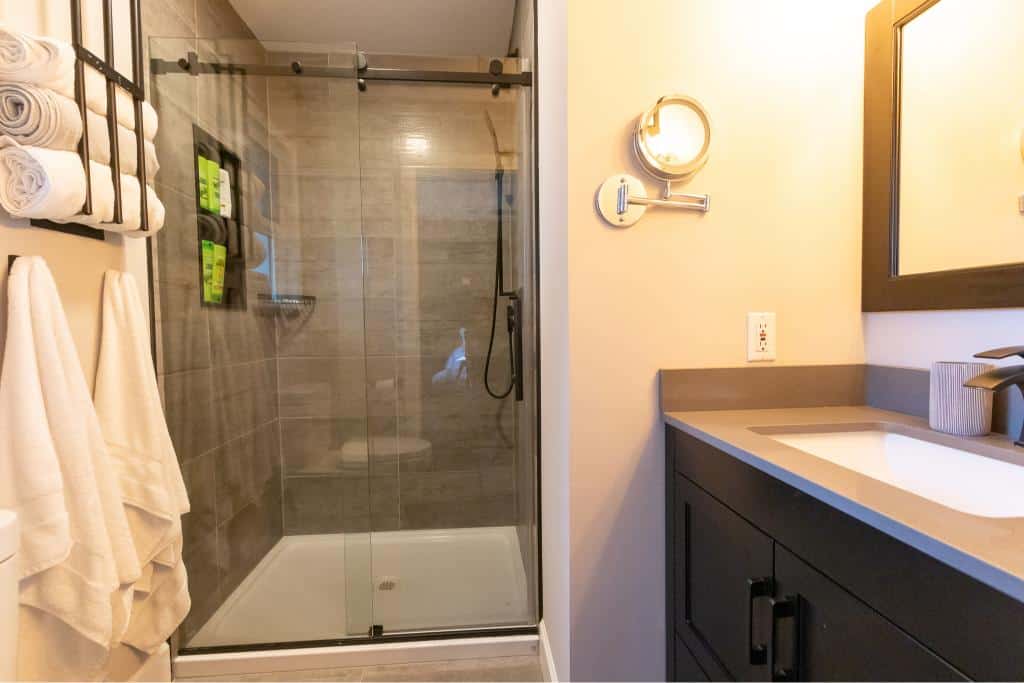 Shower enclosure with glass doors and modern tiling in a contemporary bathroom, featuring towel storage and bathroom accessories for a stylish and functional space.