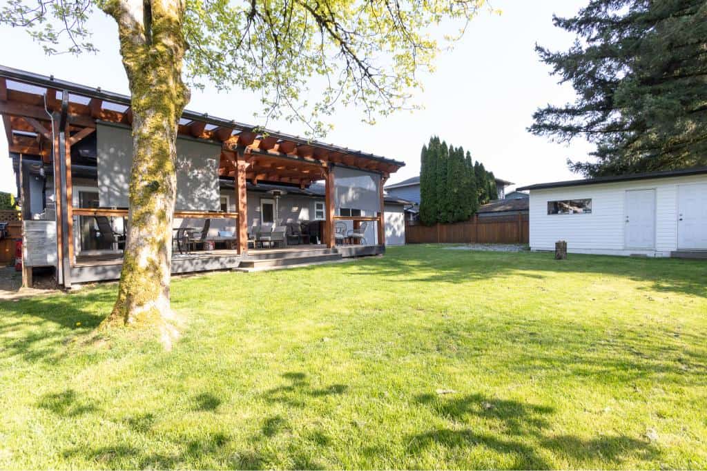 Beautiful backyard with lush green lawn, spacious deck area, and mature trees, perfect for outdoor living and relaxing in Victoria, BC. Ideal for homeowners and real estate investment.