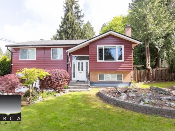 Charming red house for sale in Vancouver with lush landscaping and a well-maintained yard, perfect for families. Orca Realty Inc. offers expert real estate services in British Columbia.