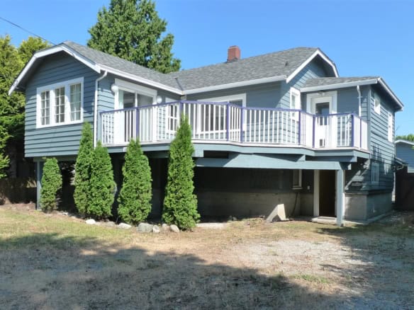 Charming blue two-story houses with elevated decks, surrounded by lush greenery and mature trees in a suburban neighbourhood, ideal for family living and outdoor entertaining.