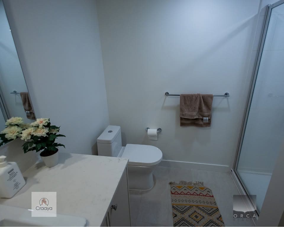 Modern bathroom with clean white fixtures, beige towels, and decorative accents, showcasing updated features and a spacious shower for舒适和实用性.