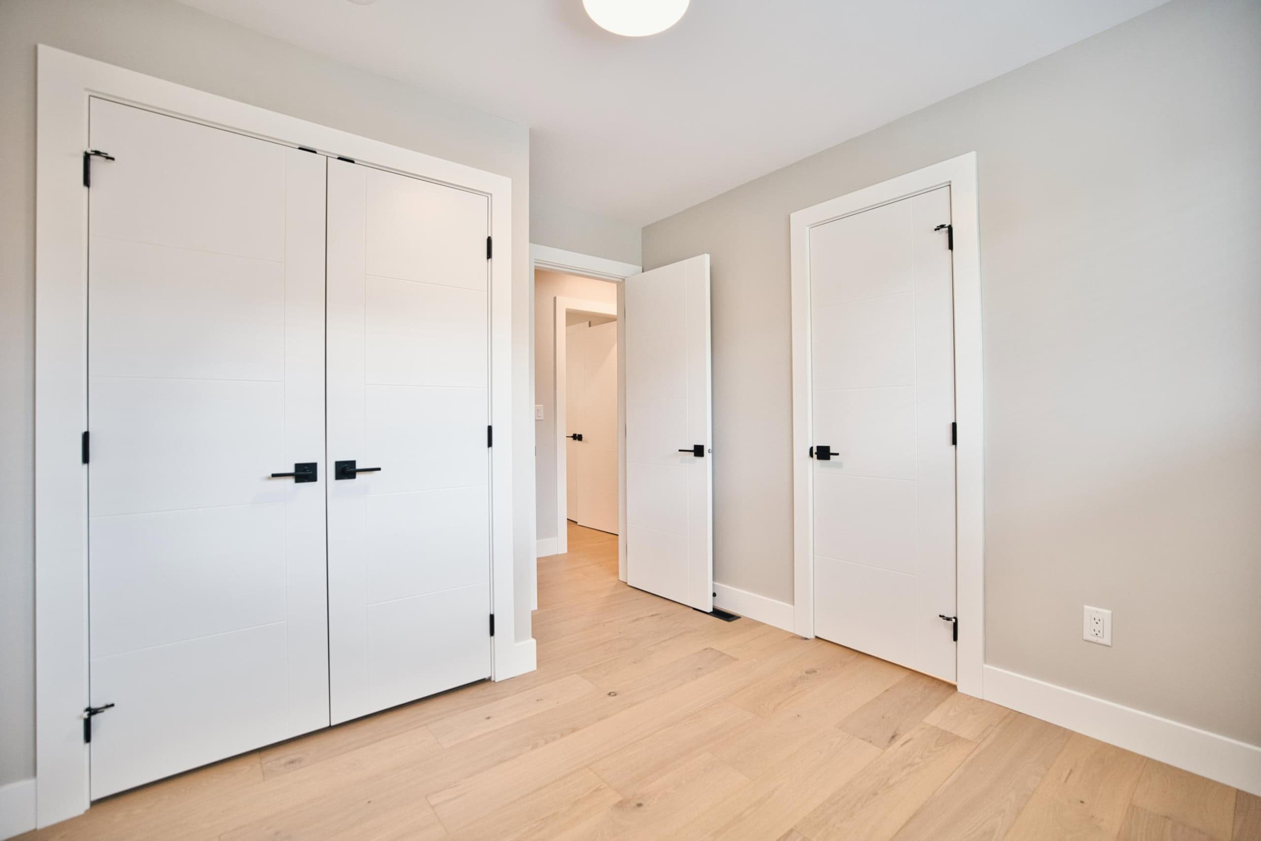 Bright modern home interior with white custom closet doors and light hardwood flooring - perfect for real estate listing in Vancouver.