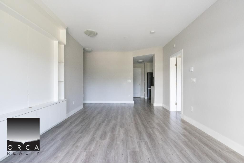 Bright and spacious modern living room with light grey flooring, minimalist white built-in shelving, and neutral wall colours, ideal for Vancouver Island real estate buyers.