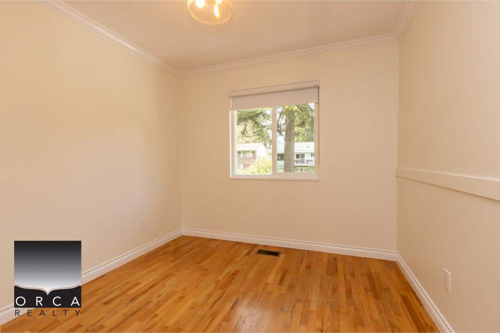 Bright and cozy bedroom with hardwood flooring and a large window providing natural light, perfect for Vancouver and GTA homebuyers seeking a comfortable space.