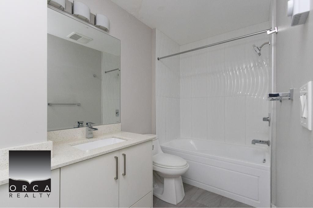 Bright modern bathroom with white cabinetry, sleek vanity, and bathtub with shower, perfect for Vancouver Island homes.