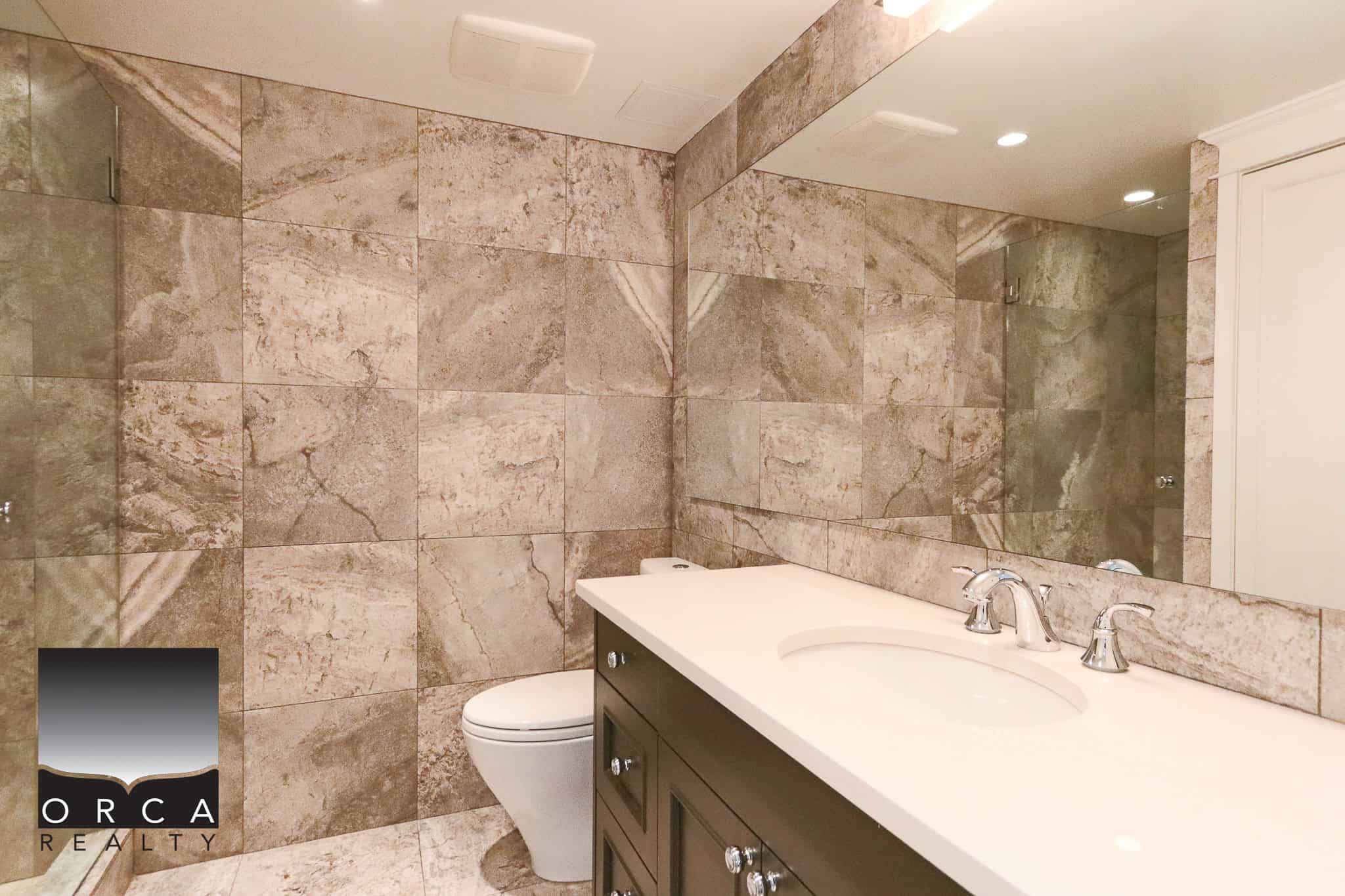 Bright modern bathroom featuring tile walls, a sleek vanity with a large mirror, and contemporary fixtures, perfect for Vancouver real estate listings.