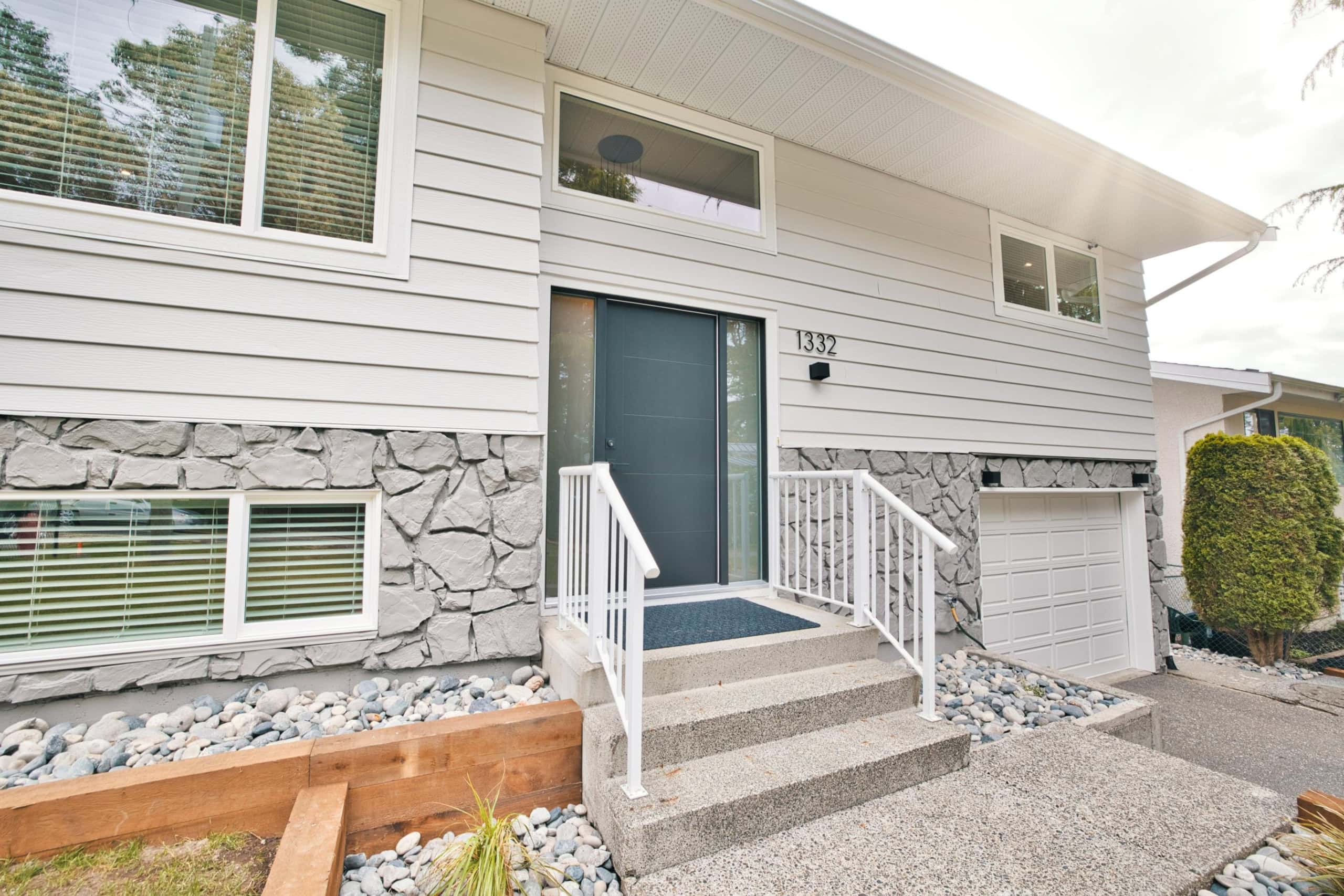 Modern suburban home with a sleek front door, stone accents, and landscaped steps, offering prime options for Vancouver-area real estate and property investment in British Columbia.