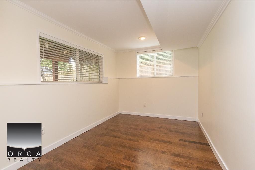 Bright empty room with hardwood flooring, white walls, and large windows providing natural light, ideal for Vancouver area real estate listings.