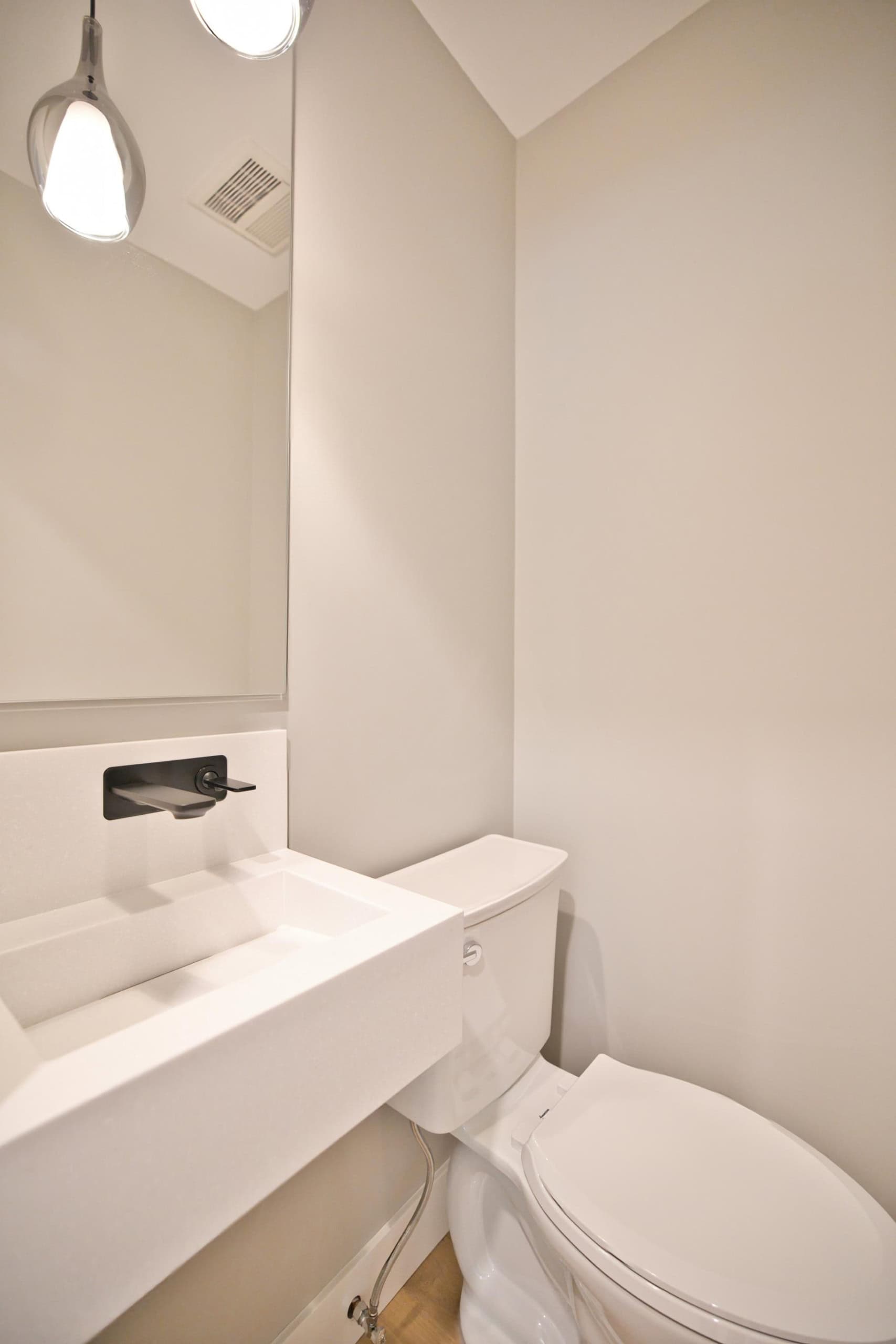 Modern minimalist bathroom with compact sink and toilet, featuring neutral-colored walls, sleek fixtures, and contemporary design, ideal for Vancouver Island real estate.
