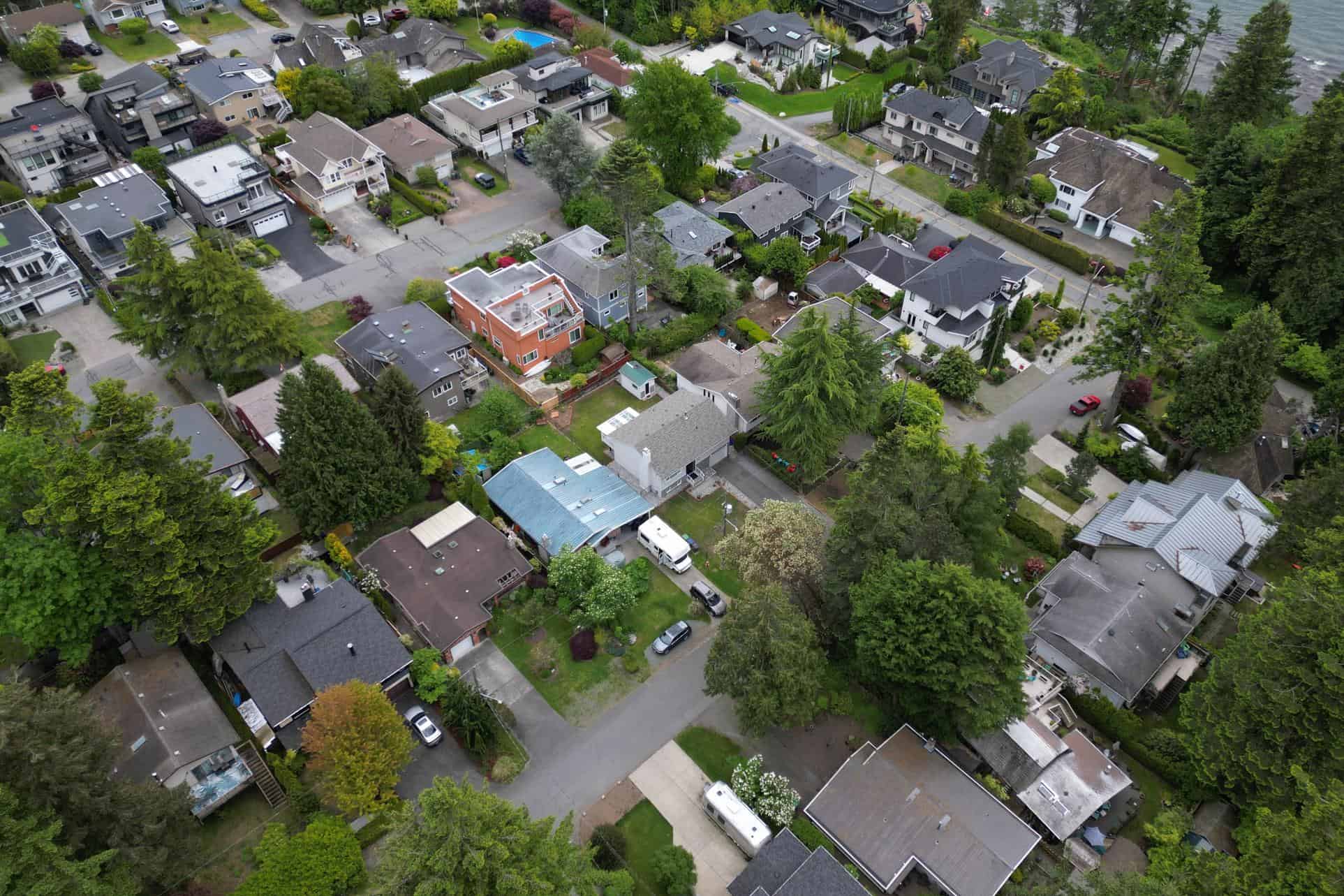 Aerial view of a residential neighbourhood with diverse homes, lush greenery, and tree-lined streets, showcasing Vancouver-area houses for sale and real estate services by Orca Realty Inc.