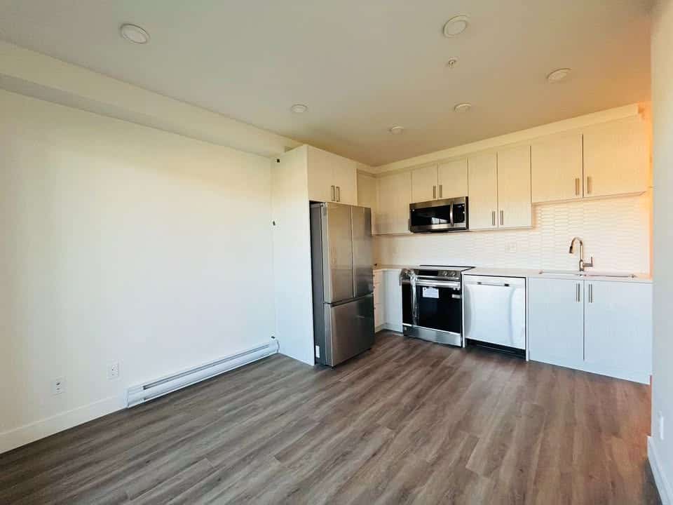 Bright modern kitchen with stainless steel appliances, white cabinetry, and wood-look flooring, perfect for Vancouver real estate and condo listings.