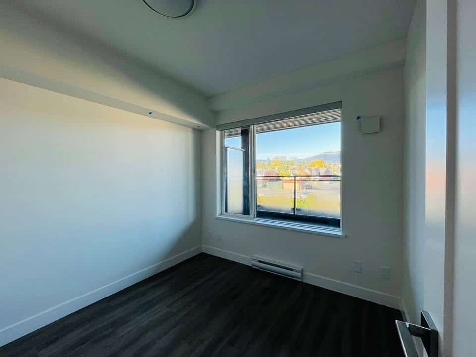 Bright empty apartment room with large window showing scenic views, modern dark flooring, clean white walls, ideal for Vancouver real estate buyers, listed by Orca Realty Inc.