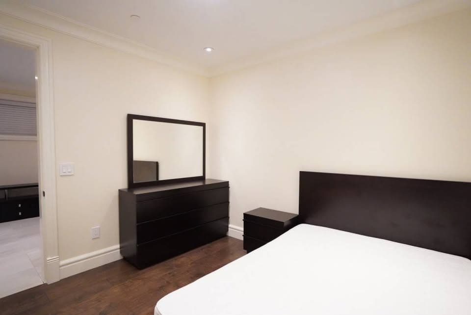 Modern bedroom with black furniture and white walls, showcasing a contemporary interior design for Vancouver real estate.