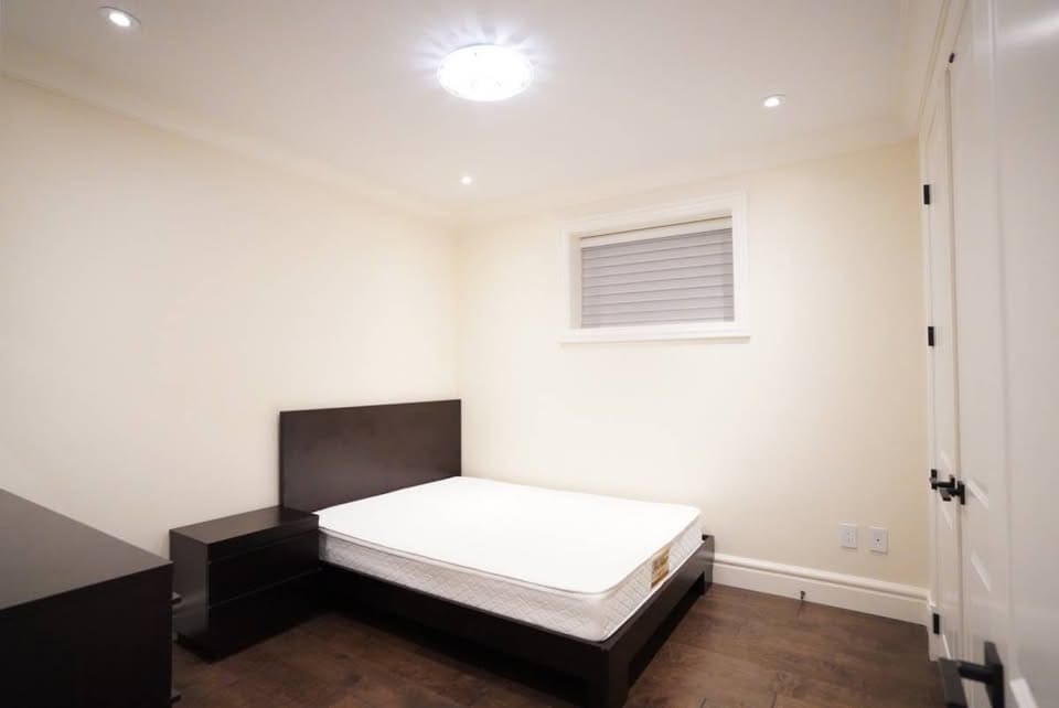 Modern minimalist bedroom with a comfortable bed, sleek black furniture, and neutral tones, ideal for Vancouver real estate listings or property rentals.