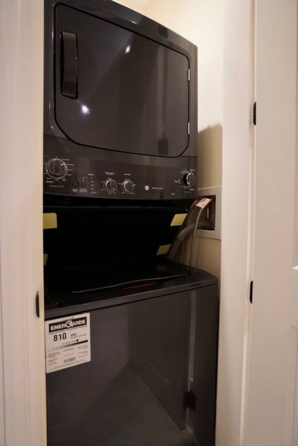 Stacked washer and dryer unit in a laundry closet, modern black appliances with energy efficiency label, ideal for condominium or apartment living, showcasing convenient laundry facilities.
