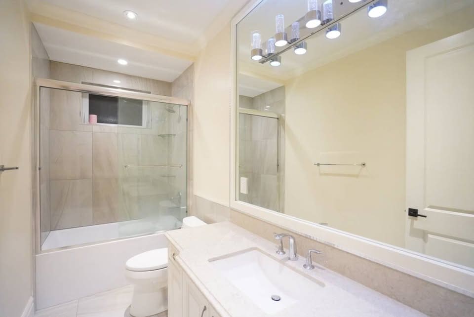 Modern bathroom featuring a glass-enclosed shower, white vanity, and contemporary lighting, showcasing high-quality home renovation services by Orca Realty Inc.