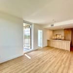 Bright open-concept living space with modern kitchen and access to balcony, ideal for Vancouver real estate buyers.