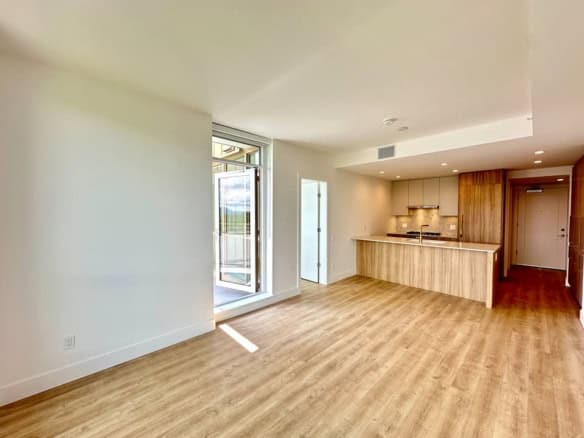 Bright open-concept living space with modern kitchen and access to balcony, ideal for Vancouver real estate buyers.