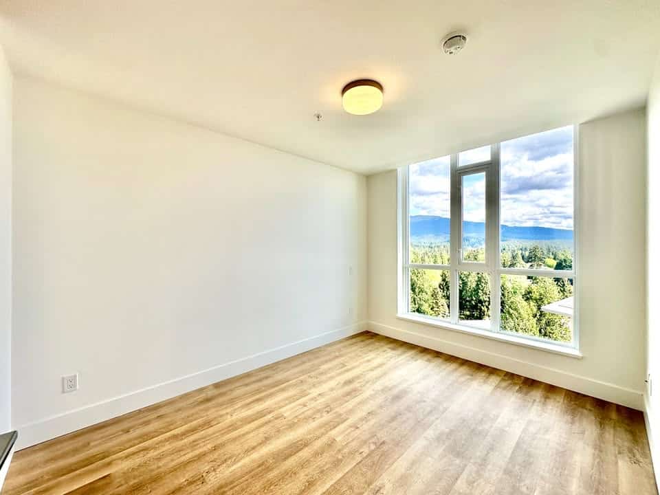 Bright, spacious apartment with large windows offering stunning mountain and forest views, featuring modern flooring and plenty of natural light, ideal for Vancouver real estate buyers.