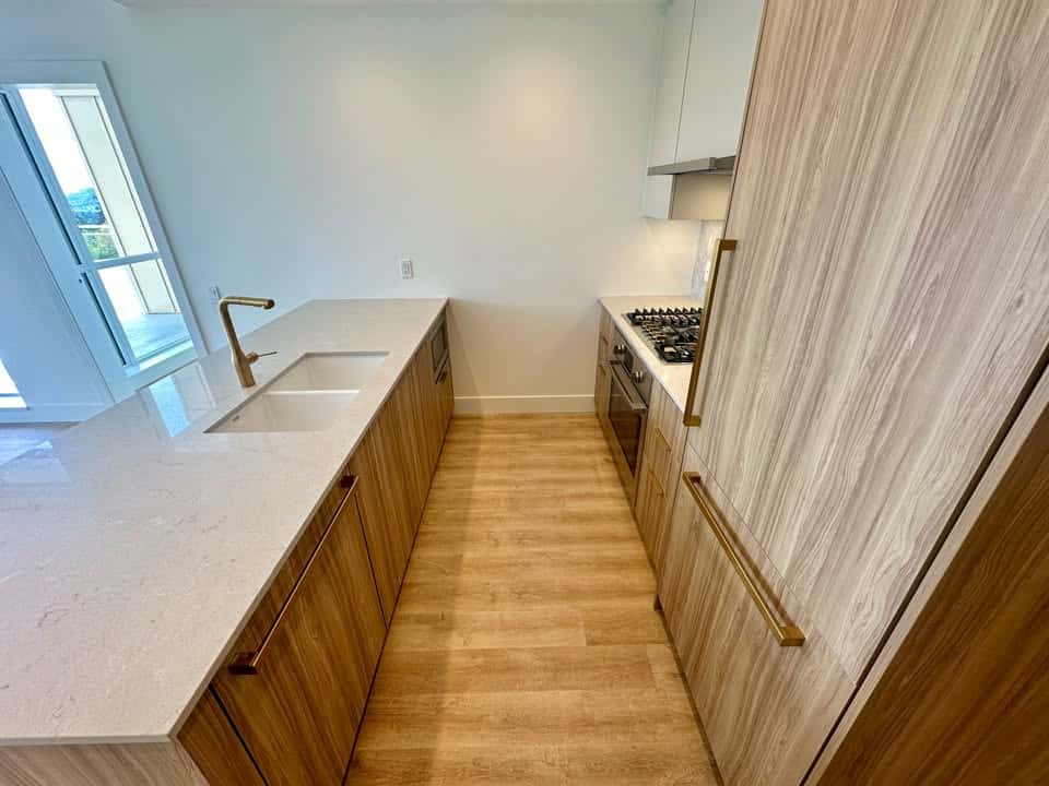 Modern kitchen interior with wooden cabinetry, white countertops, and stainless steel appliances, featuring natural light and minimalist design, ideal for homebuyers seeking contemporary living spaces.